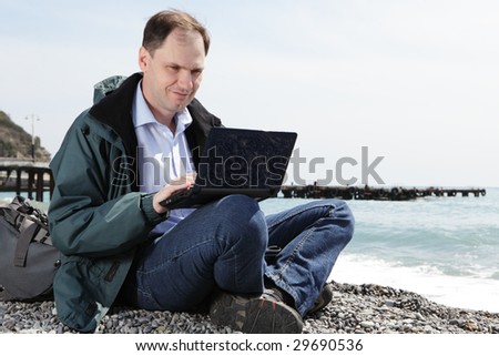 Man with laptop and backpack on beach
