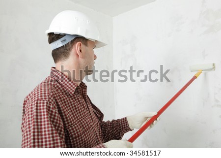 Construction worker paints the wall