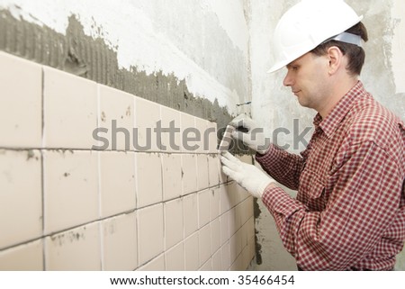 Man installs ceramic tile on a wall