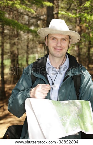 Hiker with map and compass in forest