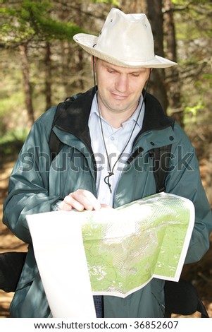 Hiker with map and compass in forest