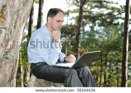 Businessman with laptop in the forest