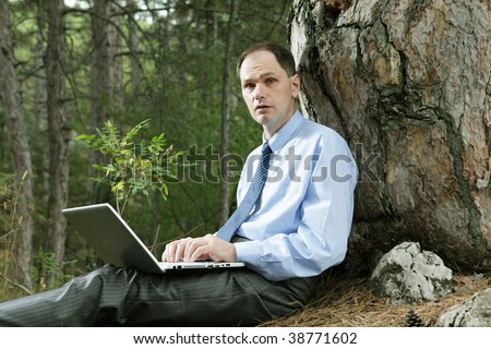 Businessman with laptop in the forest