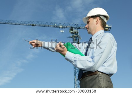 Manager with a clipboard against modern crane