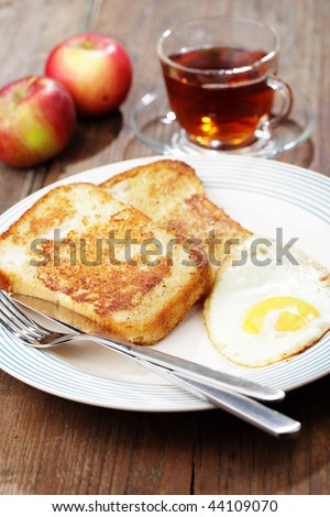 Breakfast with french toasts, fried egg, apples, and tea