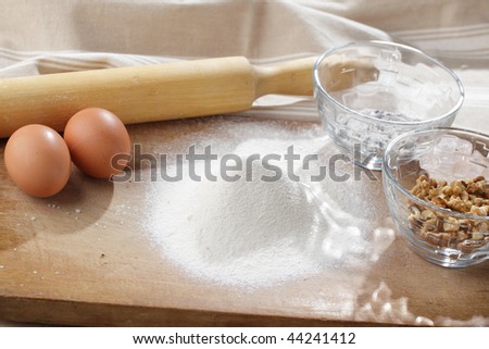 Ingredients for cookies and a rolling pin on a wooden board