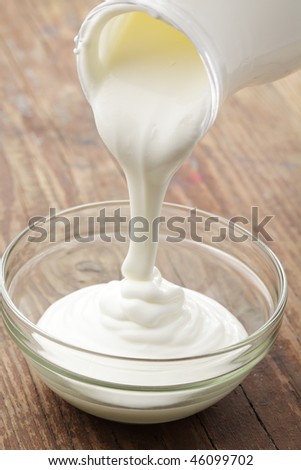 Sour cream pouring into a glass bowl