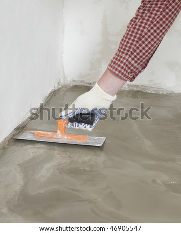 Construction worker spreading wet concrete on a floor