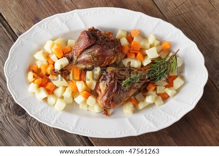 Roasted turkey legs with vegetables on white dish
