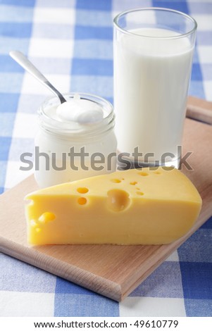 Yellow cheese, cup of milk, and a jar with sour cream