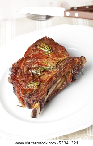Roasted rib steak with rosemary on white plate