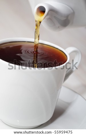 Pouring black tea in a cup