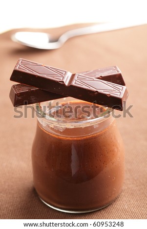 Jar with chocolate yogurt and two sticks of dark chocolate