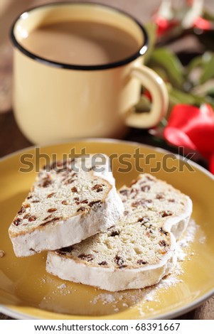 Christmas stollen with raisins closeup against the mug of coffee with milk and Christmas wreath