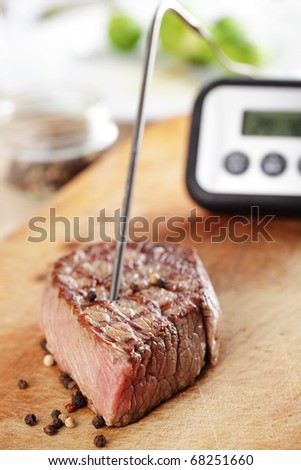 Grilled steak on the cutting board with temperature controller inside