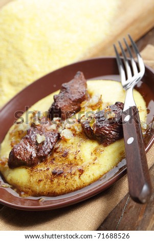 Polenta with beef meat on the brown plate