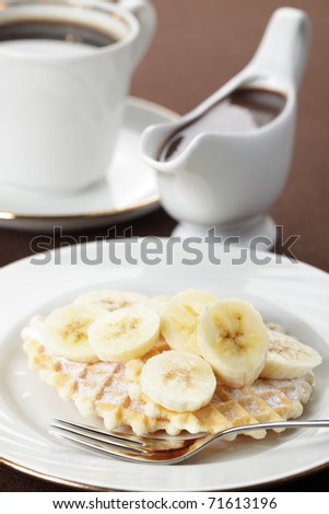 Waffle with banana, sugar powder, chocolate sauce, and coffee