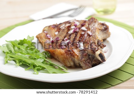 Grilled rib steak with red onion and rocket salad