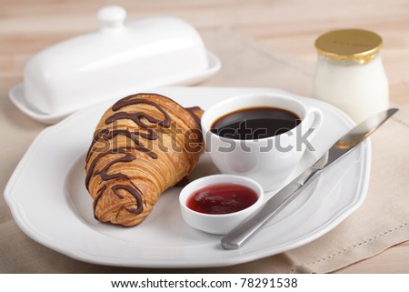 French breakfast with coffee, croissant, jam, butter, and yogurt