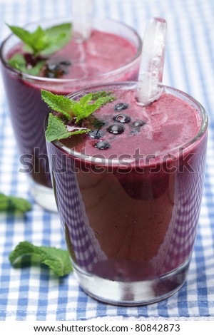 Blueberry smoothie with berries, mint leaf, and ice stick