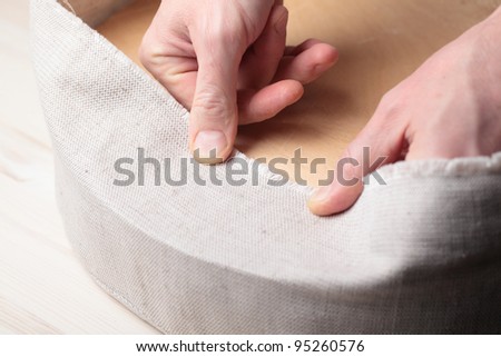 Man upholstering a round stool seat