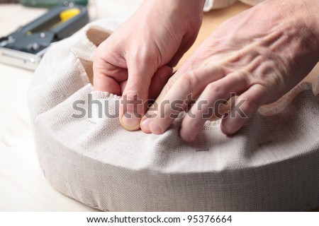 Man upholstering a round stool seat
