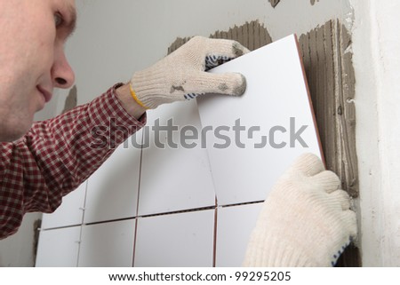Contractor installing tiles on a wall