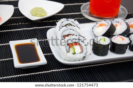 Sushi set on white plate. Black bamboo mat background