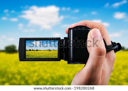Video camera or camcorder recording yellow field and blue sky
