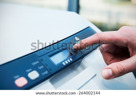 Man holding finger on start button of laser printer