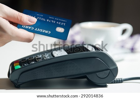 Woman hand using payment terminal in restaurant