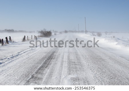 rural road in bad driving conditions. drifting blowing snow.