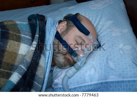 mature man (photographer is the model) sleeps on side using cpap nasal mask to treat sleep apnea