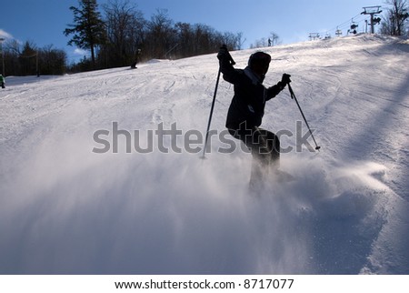 silhouette of skier stopping suddenly creating a spray of now towards the camera