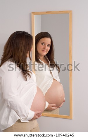 Pregnant woman shows belly in mirror