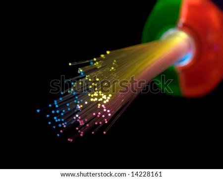 Bundle of optical fibers lit by multi-coloured lights (in a children\'s toy).  isolated on black; selective focus