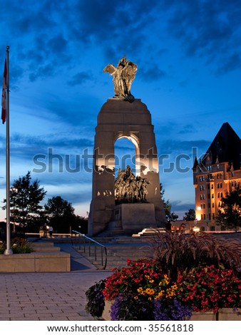 National war memorial at dusk with Chateau Laurier Hotel in background.