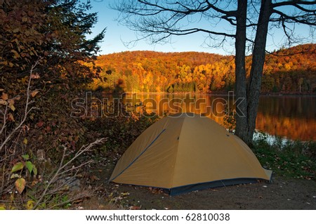 tent pitched next to an idyllic lake with blazing autumn colours, lac taylor, quebec