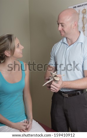 Chiropractor busy with patient show her a back bone