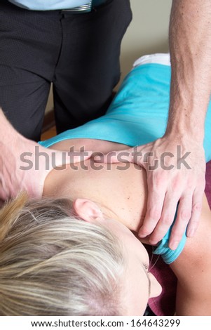 Chiropractor massage his young female patient shoulders