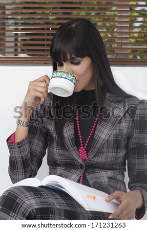 Indian Business Woman Reading a book and drinking coffee