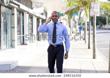 Young Attractive Black Business Man on his cellphone while walking, talking