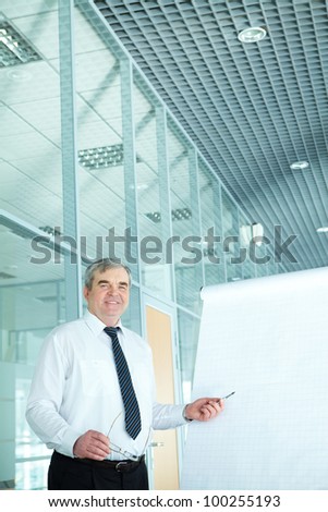 Portrait of elderly teacher pointing at whiteboard in office