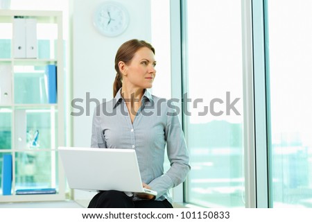 Business lady with laptop looking outside the window, searching for inspiration and new ideas