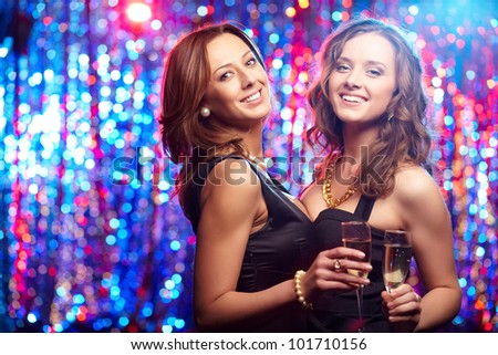 Cheerful young beauties with flutes of champagne having a nightclub party