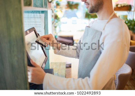 Waiter of modern cafe or restaurant entering payment information after serving client