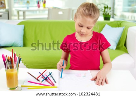 Portrait of lovely girl drawing with colorful pencils at home