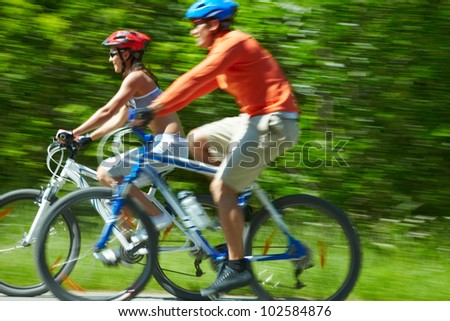 Image in motion of two bicyclists riding down country road