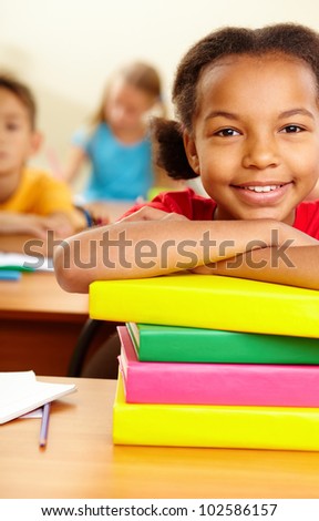 Portrait of lovely girl with stack of books looking at camera at workplace