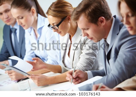 Female looking through business papers at briefing among her colleagues